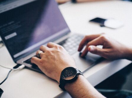 man with smart watch working on laptop
